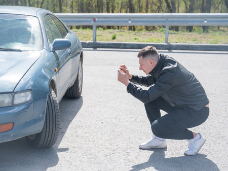 Caucasian man looks at and photographs deformation on his car bodyの写真素材