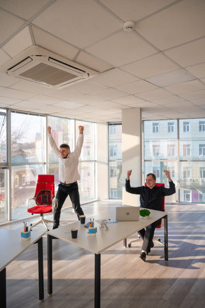 Two Caucasian men celebrate success at workの写真素材