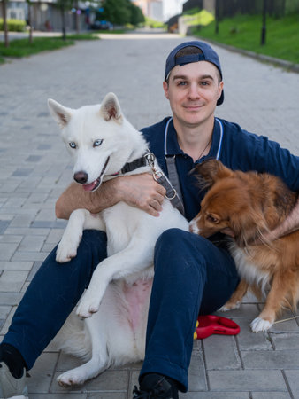 A man hugs his two dogs while on a walkの写真素材