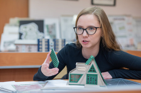 Caucasian young woman making a model of a building. Student of the construction university