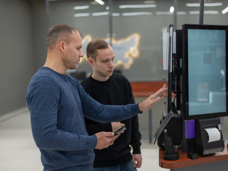 Two men use a self-checkout machine at a store