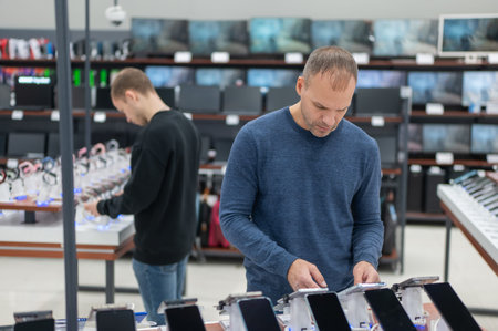 Two Caucasian men are choosing a smartphone in a store