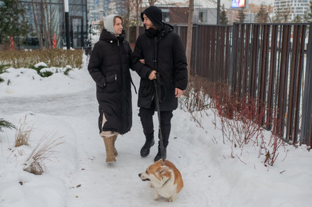 A Caucasian couple walks their corgi dog in winterの写真素材