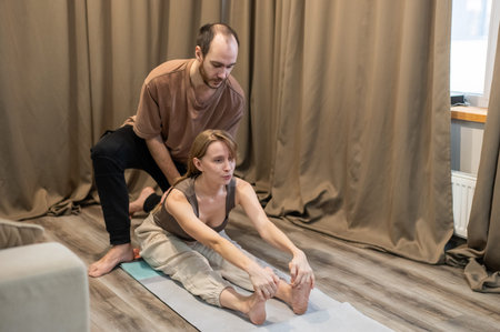 A Caucasian couple practices yoga at home