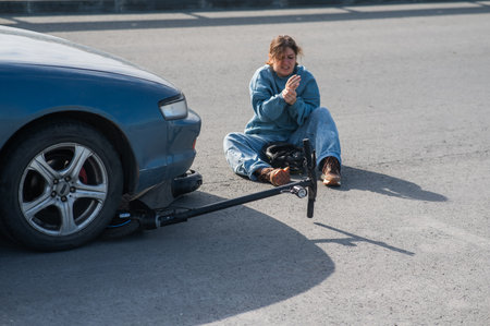 A woman on a scooter after being hit by a carの写真素材