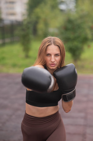 A Caucasian woman practices boxing outdoors