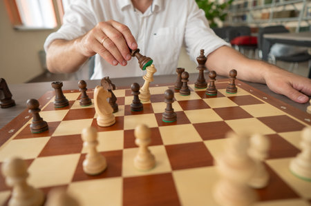 Close up of hands of middle aged man playing chess