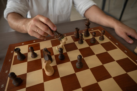 Close up of hands of middle aged man playing chess