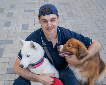 A man hugs his two dogs while on a walkの写真素材