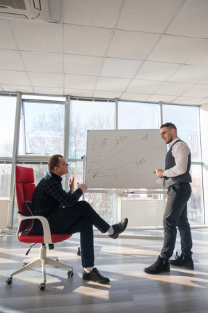 Two Caucasian men discussing work at a white board