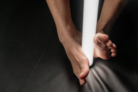 A woman holds an LED lamp with her feet.