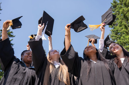 Young women of different nationalities pull graduation caps up