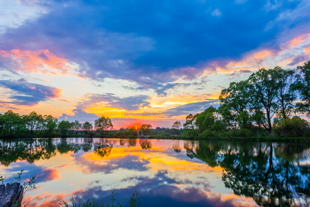 red clouds at sunset reflected in waterの写真素材