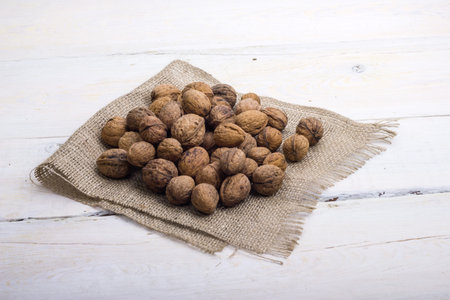 walnuts on a white table with a bag nuts and shells on white table with burlap