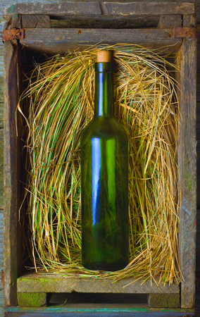 beer bottle in an old box with straw on a wooden tableの写真素材