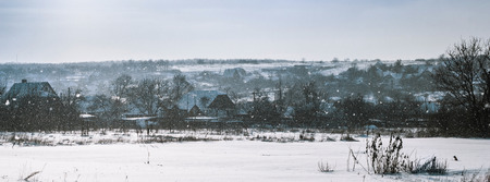 panorama of the village at Winter with falling snowの写真素材