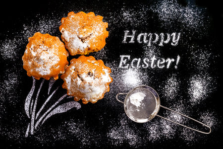 Cooking cupcakes for Easter with a greeting in the form of powdered sugar on a dark background