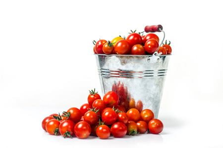Homemade tomatoes in a bucket on a white background for isolationの写真素材