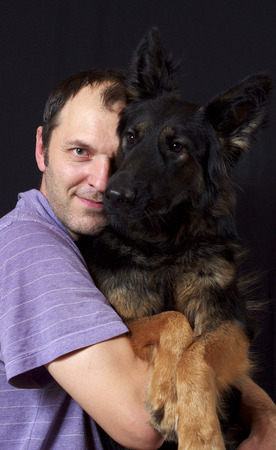 A man and his dog sit together. Isolation. Dark background.の写真素材