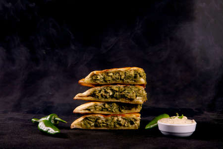 Green tikka stuffed naan with green chillies with garlic mayo dipper smoke in the backgroundの写真素材