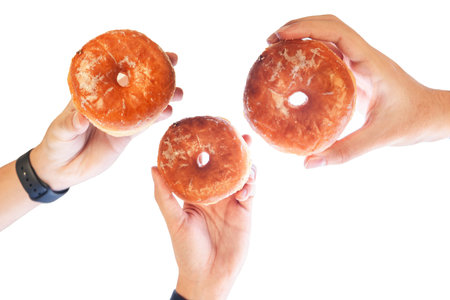 Different hands holding glazed doughnuts in different angles