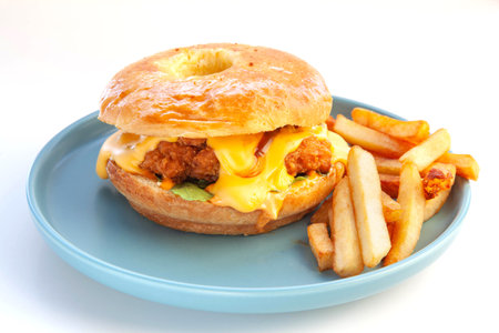 Fried chicken burger with brioche donut bun and fries served on a blue plate.の写真素材