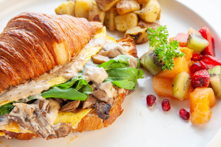 Mediterranean scrambled egg croissant sandwich with fruits and potatoes.の写真素材