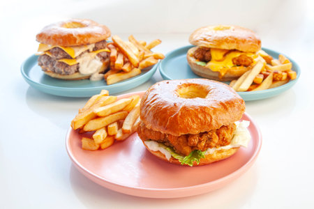 Crispy breaded fried chicken brioche donut bun burger served with hand cut fries on pink plate.の写真素材