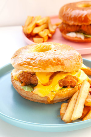 Fried chicken burger with brioche donut bun and fries holding in one hand.の写真素材