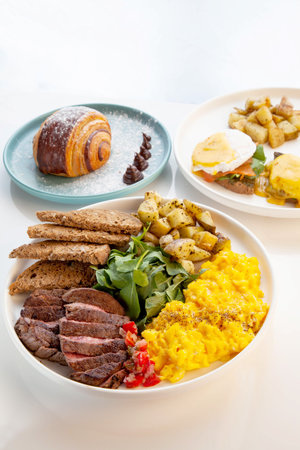 Tenderloin beef steak with scrambled eggs, rocket leaves and potatoes with a side of rye bread.の写真素材