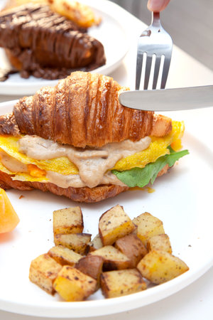 Croissant egg sandwich breakfast with fresh watermelon fruit and potatoes.の写真素材