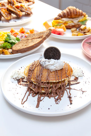 Chocolate drizzling on cut pan cake with other breakfast dishes in the background.の写真素材