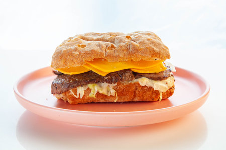 Philly cheese steak ciabatta sandwich served on a pink plate.の写真素材