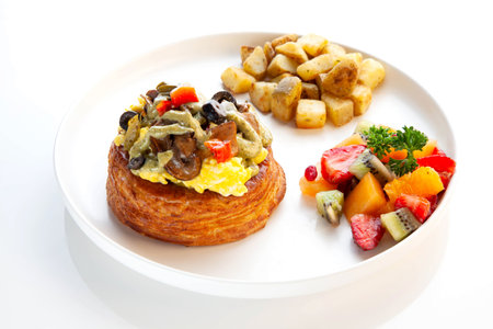 Danish pastry topped with scrambled eggs, olives in pesto sauce.の写真素材