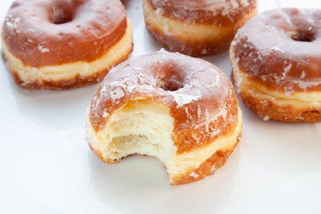 Bite taken out from a brioche glazed doughnut.の写真素材