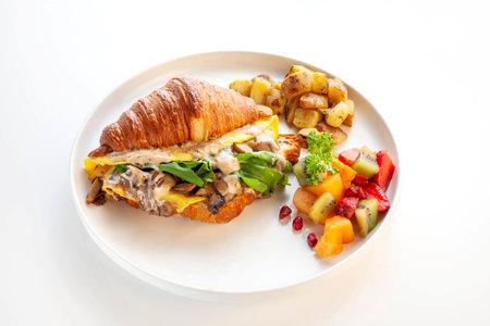 Mediterranean scrambled egg croissant sandwich with fruits and potatoes.の写真素材
