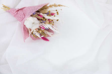 Bouquet beautiful dried flowers on a white textileの写真素材