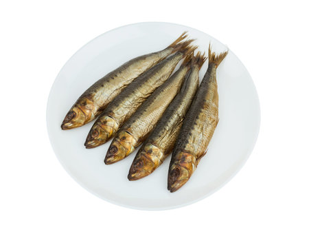 Cold smoked Capelin fish on a white plate. Isolated on a white background. Close up