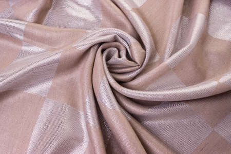 Fabric with metal thread is in a beige color, twisted in a spiral. Top viewの写真素材
