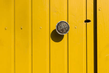 Yellow wooden door with a metal handle and a keyholeの写真素材