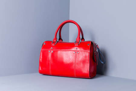 A bright red tote bag stands on a wooden gray background. The bag is decorated with white stitchingの写真素材