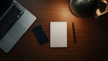 Top view of modern workplace with laptop, smartphone and notepad on wooden tableの素材