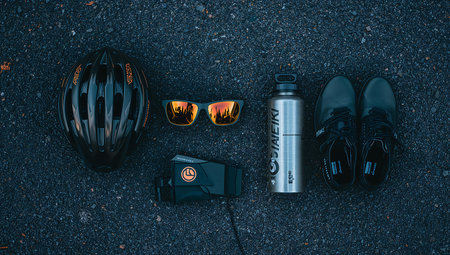 Bike helmet, sunglasses, water bottle and shoes on the roadの素材