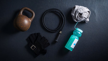 Kettlebell, black gloves and a bottle of water on a black backgroundの素材