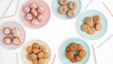 Flat lay of cookies on pink and blue plates over white background.の素材