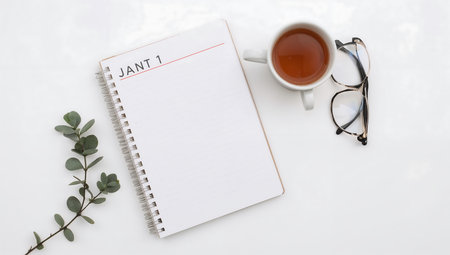 Top view of open notebook with cup of tea on white background.の素材
