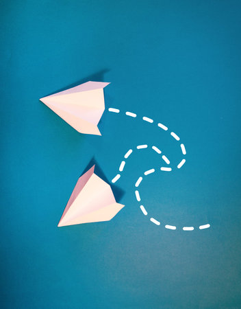 White, small, paper plane on a blue background.