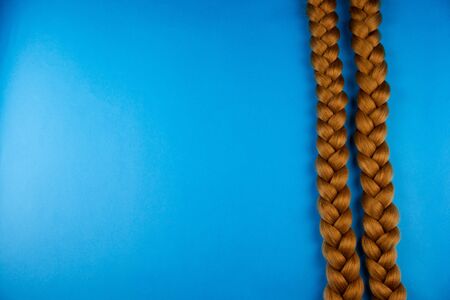 Two blond braids on a blue background, lie in parallelの写真素材