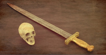 Antique sword and skull with an old brown textureの写真素材