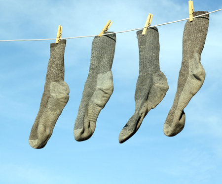 gray socks hanging on a clothesline with a blue sky in the background